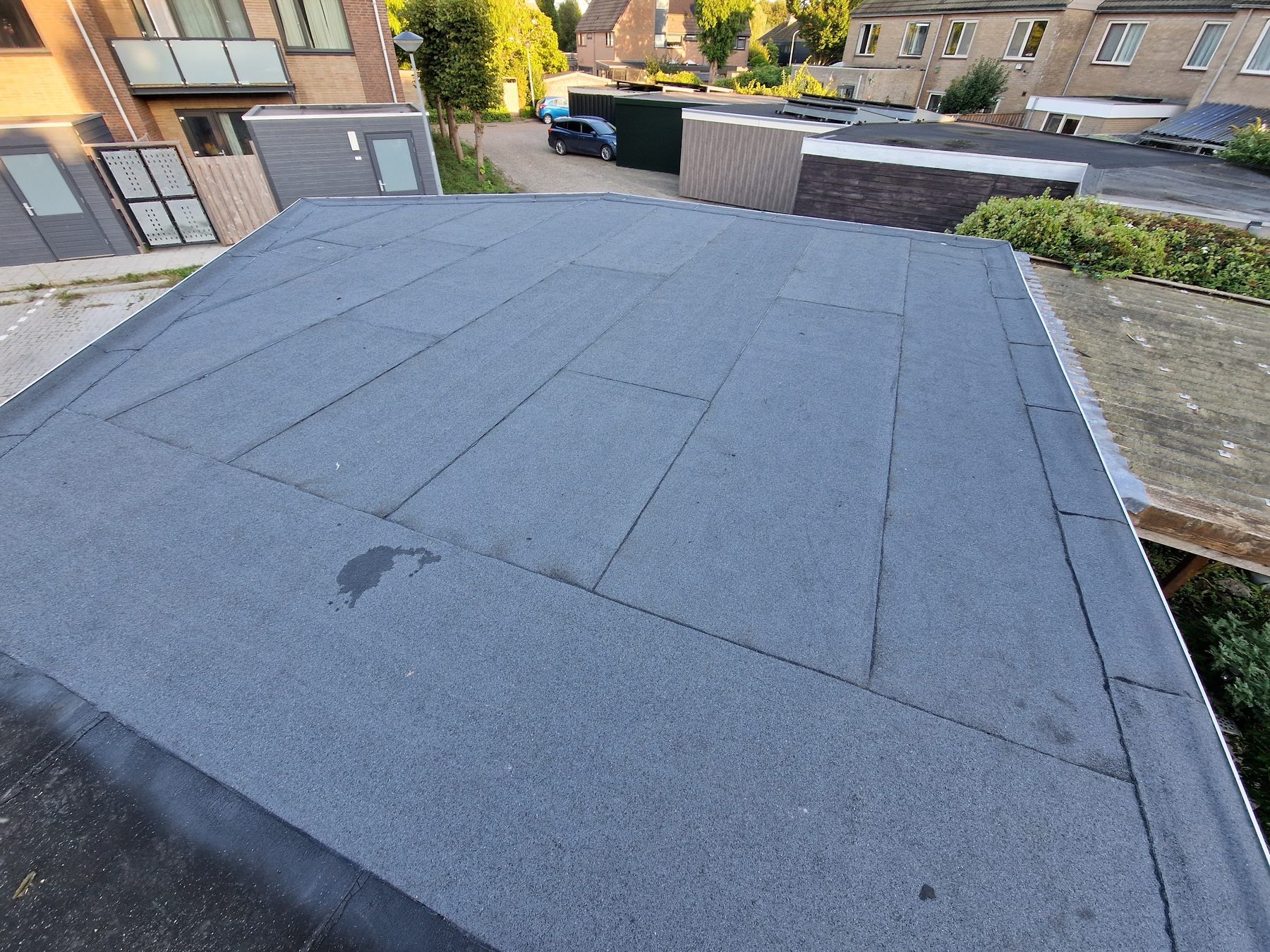 Een plat dak van een garage, net voorzien van nieuwe bitumen dakbedekking
